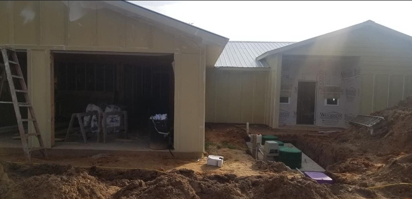 In-progress carpentry job — new construction with garage framing, exterior sheathing and metal roofing