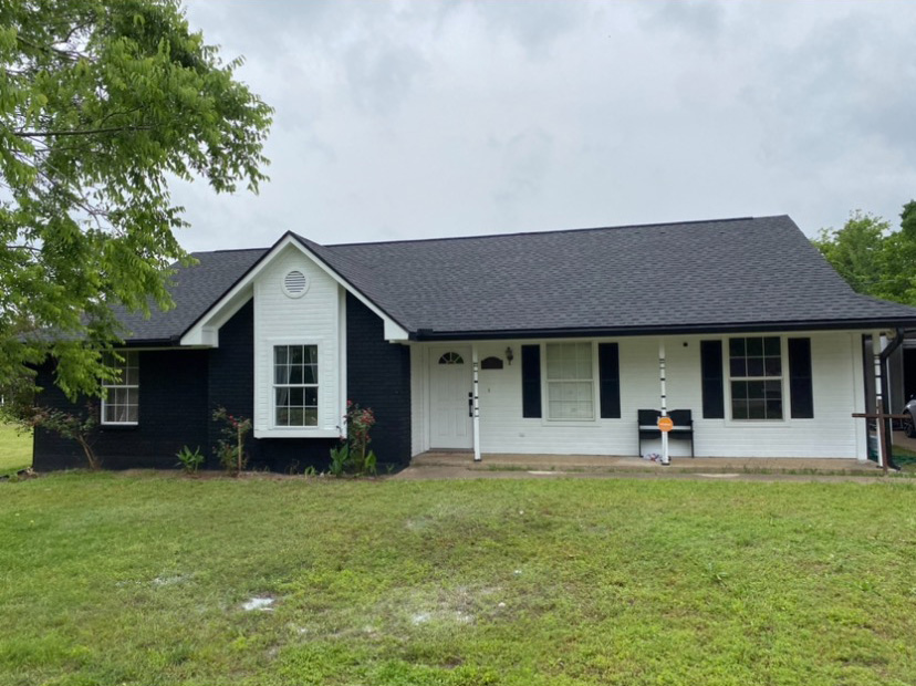 Exterior of a Texas home freshly painted by Nichol's — black brick base with crisp white trim, gables and porch