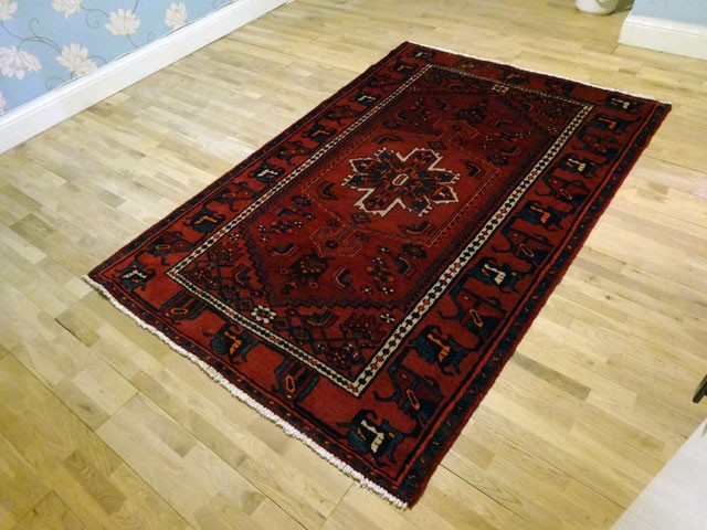 Cleaned red oriental wool rug laid out on hardwood floor
